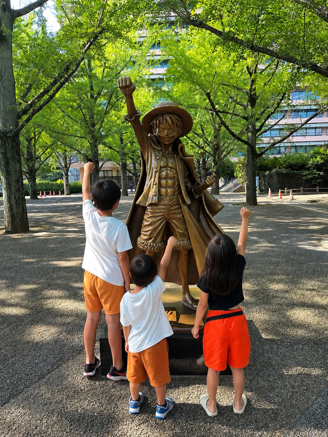 Children viewing the Luffy statue during a family trip in Kumamoto